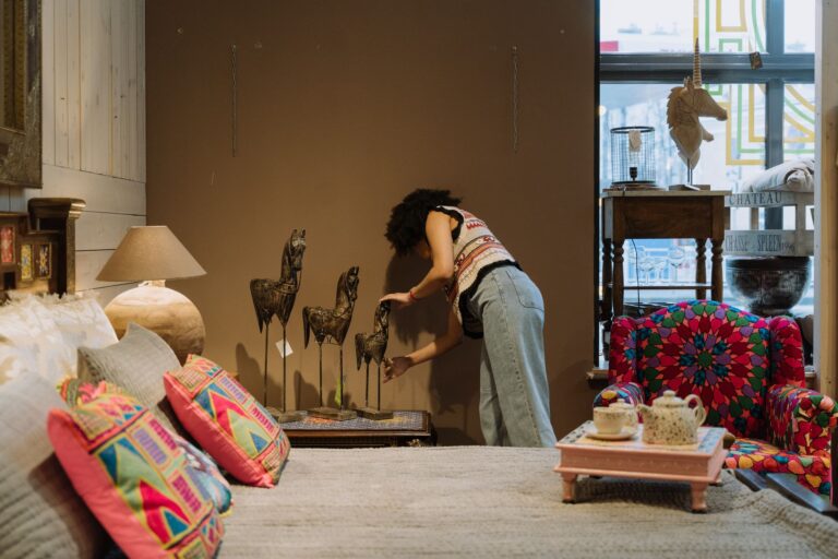 A woman arranging decor in a cozy, colorful bedroom interior.