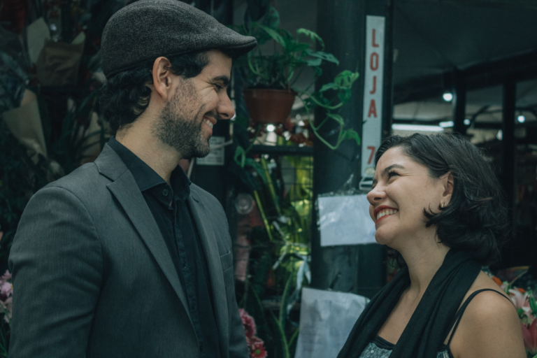 A couple sharing a joyful moment at a vibrant market outdoor setting.