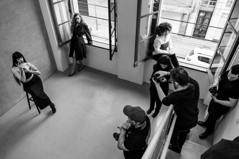 Black and white indoor photo shoot with multiple models and photographers in a modern studio setting.
