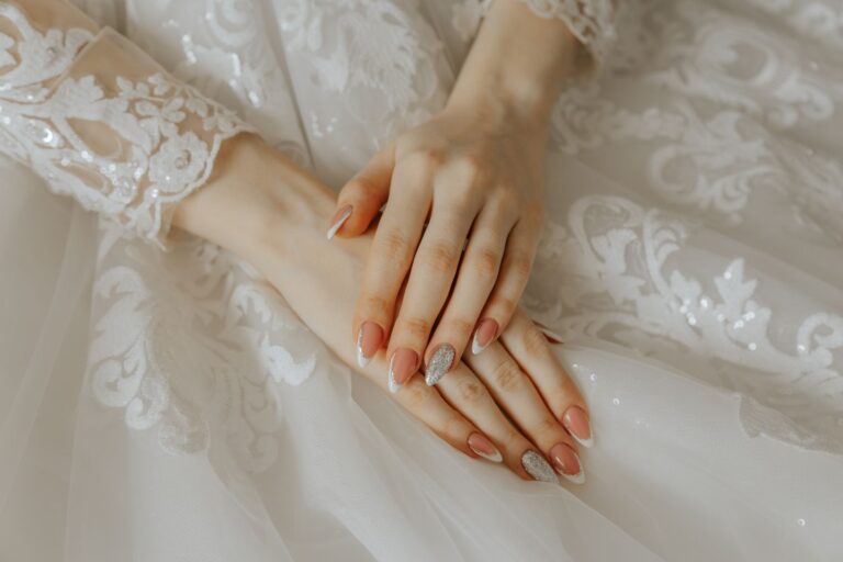 Close-up of a bride's hands on a detailed lace wedding dress, highlighting elegance and beauty.