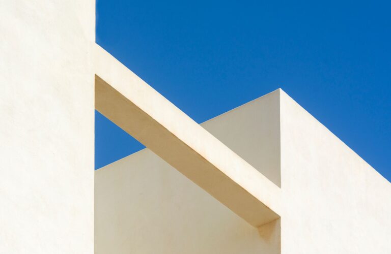 Minimalist architectural design showcasing geometric shapes against a clear blue sky.