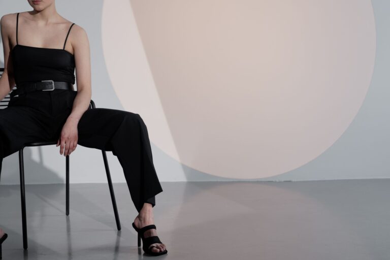 Elegant woman in black outfit posing in stylish studio with minimalist design.