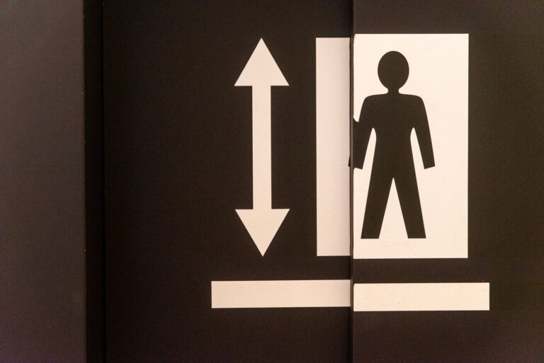 Graphic of an elevator door with a human figure and directional arrow symbol.
