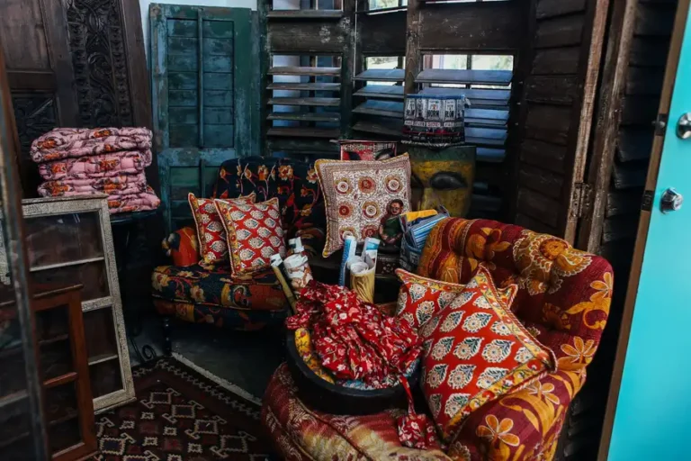A vintage-style living room featuring vibrant patterned armchairs and pillows in a rustic setting.