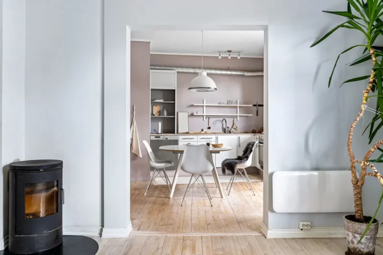 Bright open kitchen featuring modern Scandinavian design with fireplace and wood flooring.