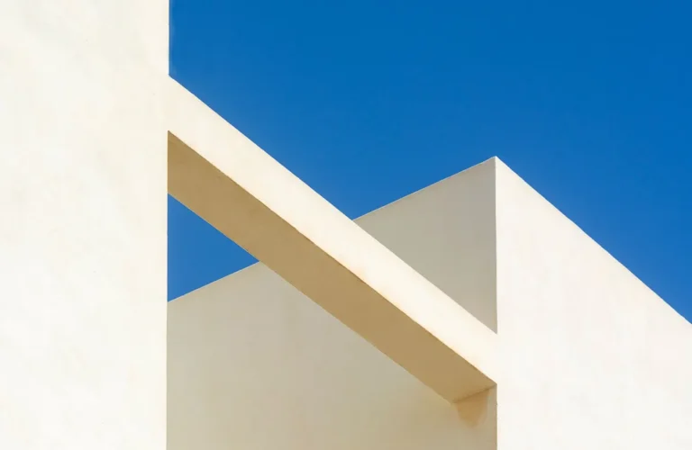 Minimalist architectural design showcasing geometric shapes against a clear blue sky.