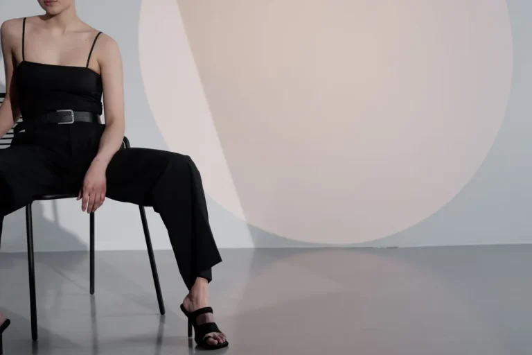 Elegant woman in black outfit posing in stylish studio with minimalist design.